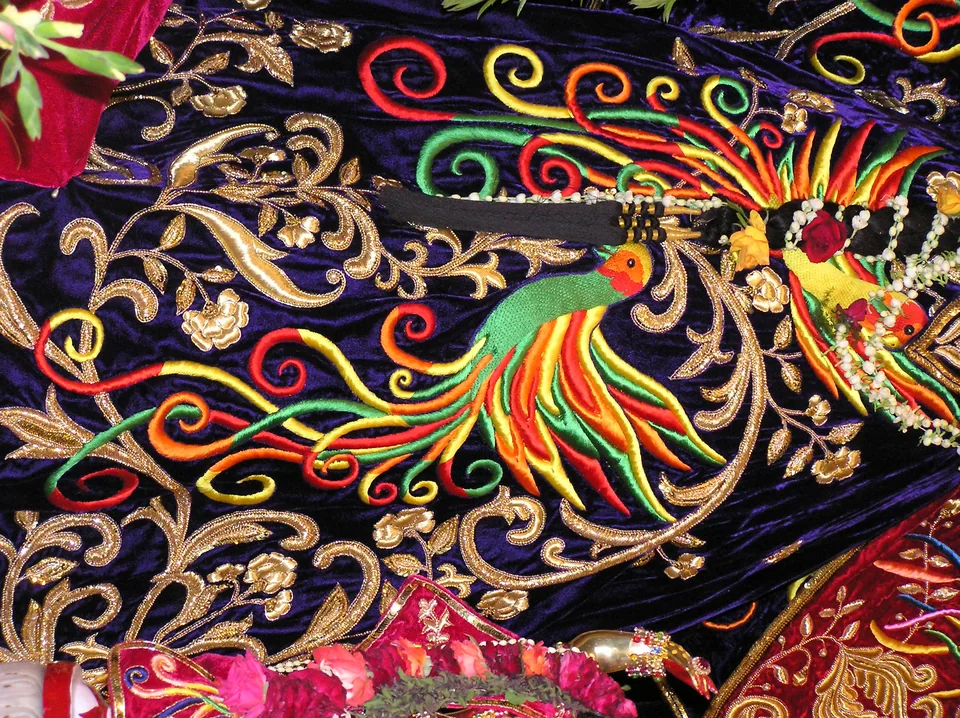 Multicoloured embroidered birds and gold-coloured leafy scrolls on a deep blue-purple background
