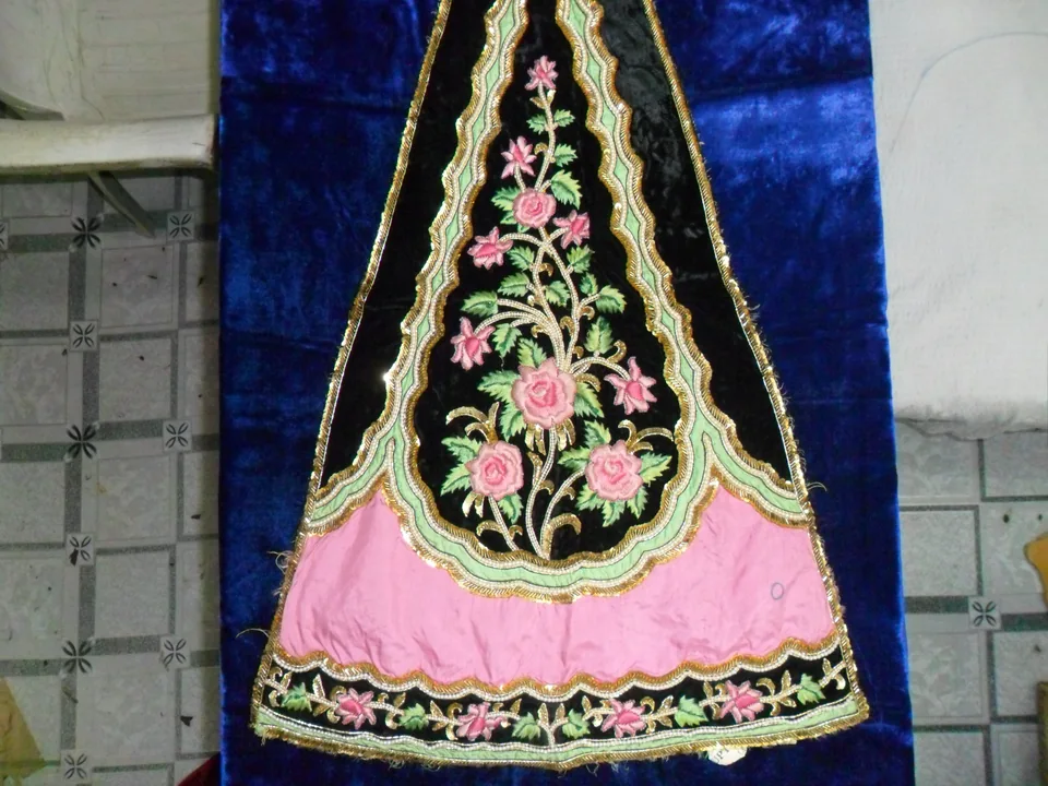 Black and pink garment laid flat with pink flowers, green leaves and scalloped gold-coloured edging