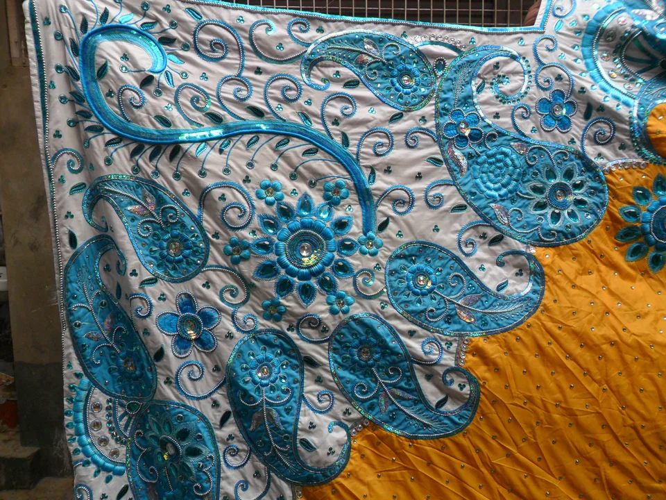 Close view of blue scrolling motifs and round floral details on a pale border beside a yellow backdrop centre
