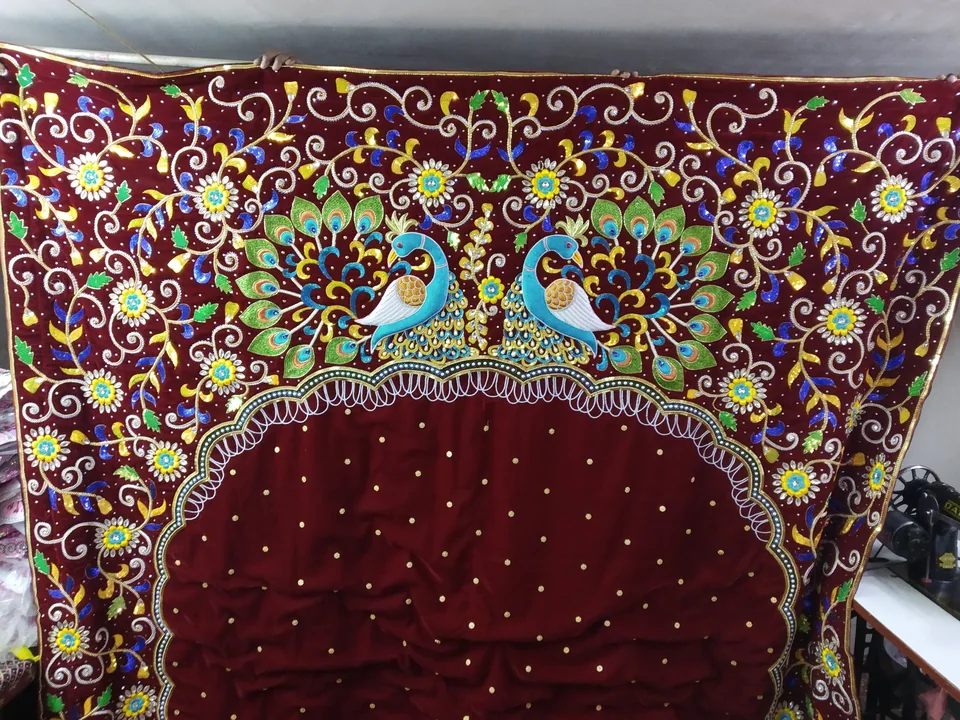 Burgundy backdrop with an arch-shaped centre, embroidered peacocks and colourful scrolling flowers