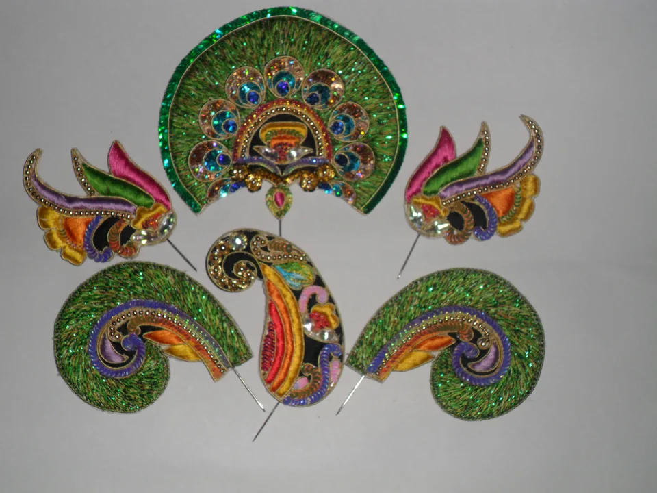 Green and multicoloured decorated crown and matching curved ornaments laid out together