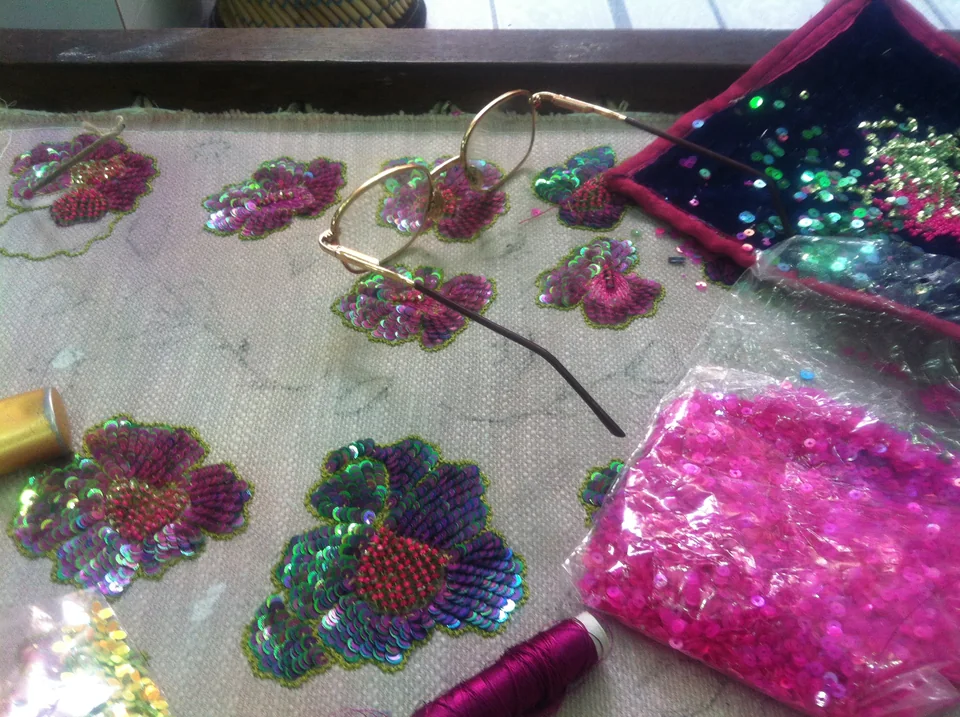 Colourful floral embroidery motifs and sequins on fabric held in a frame