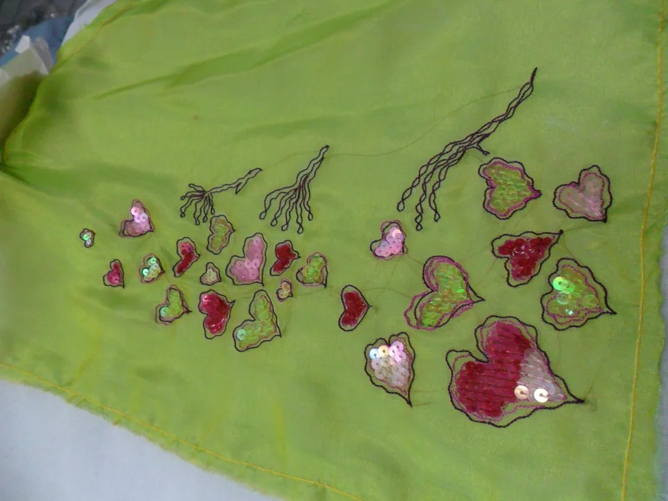 Heart-shaped outlined motifs and branching lines with pink, red and green reflective details on bright green cloth