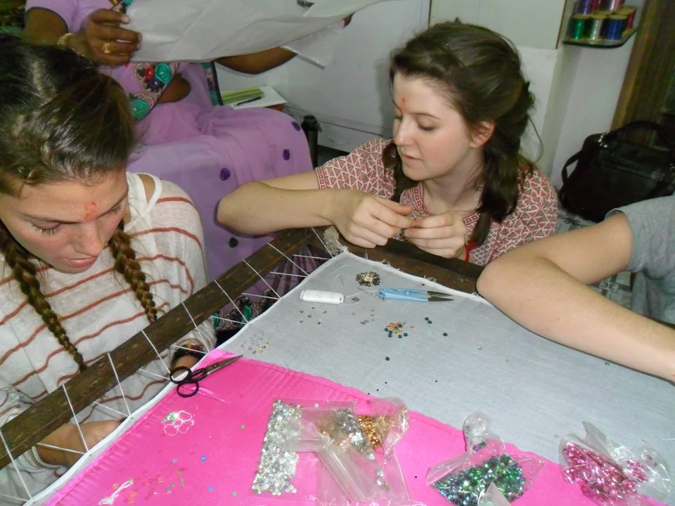 Workshop participants working closely on pink fabric in embroidery frames