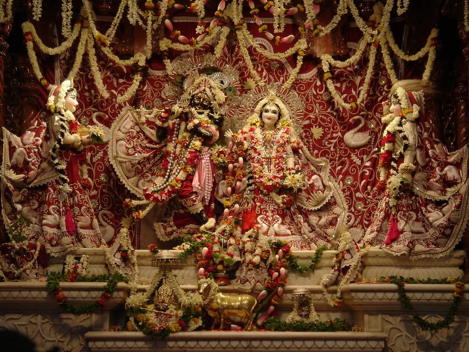 Temple deities adorned in embroidered attire, surrounded by gold and floral decorations