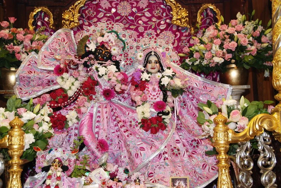 Deities in pink embroidered attire, framed by flowers