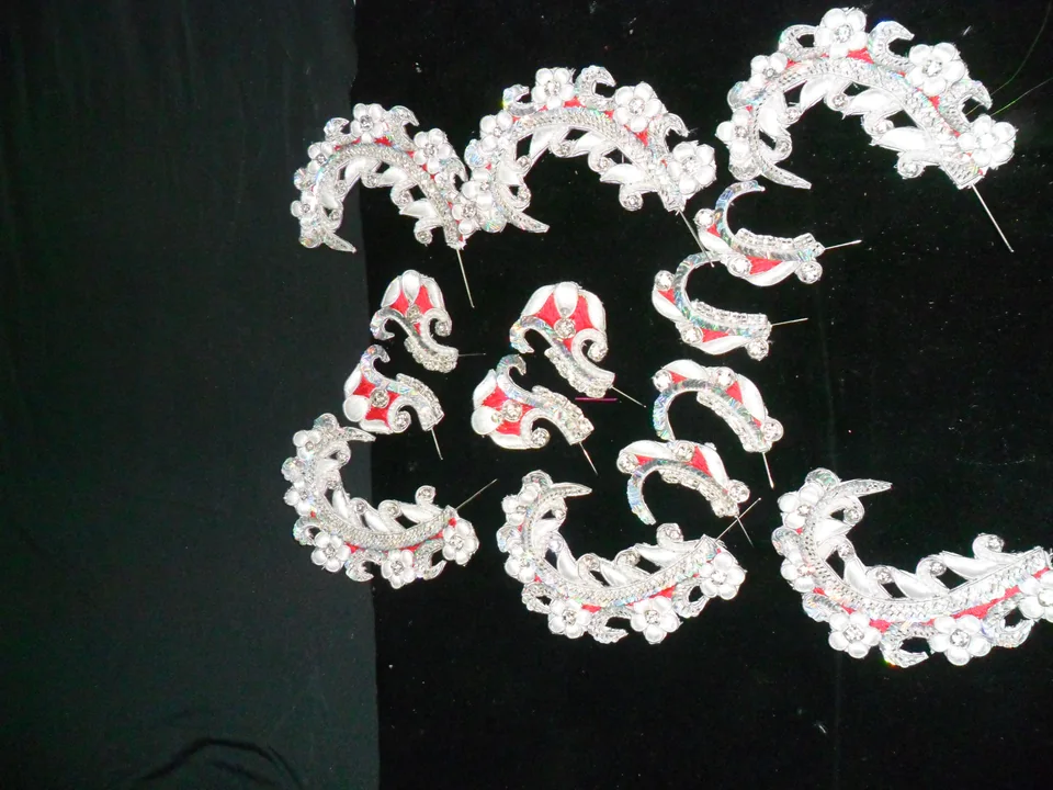 White curved ornament pieces with red-coloured accents arranged separately on a dark surface